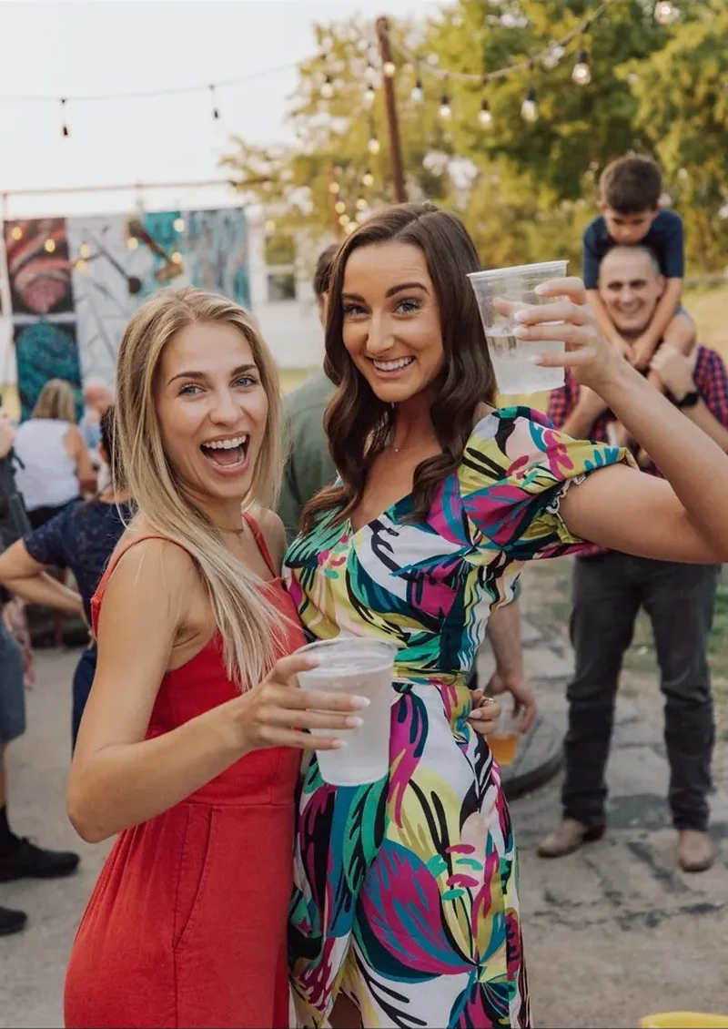 Photo d’illustration : deux invitées souriantes lors d’une fête en extérieur