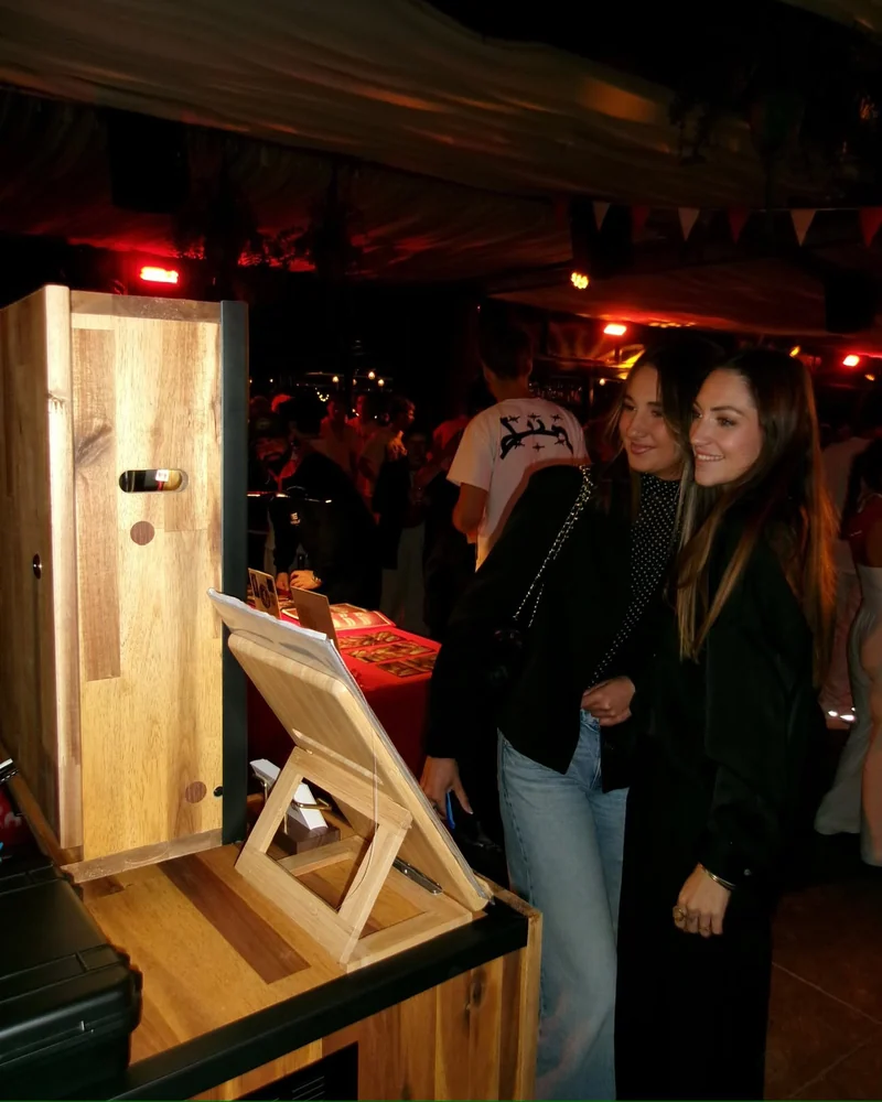 Invitées devant la borne photo en bois lors d’une soirée